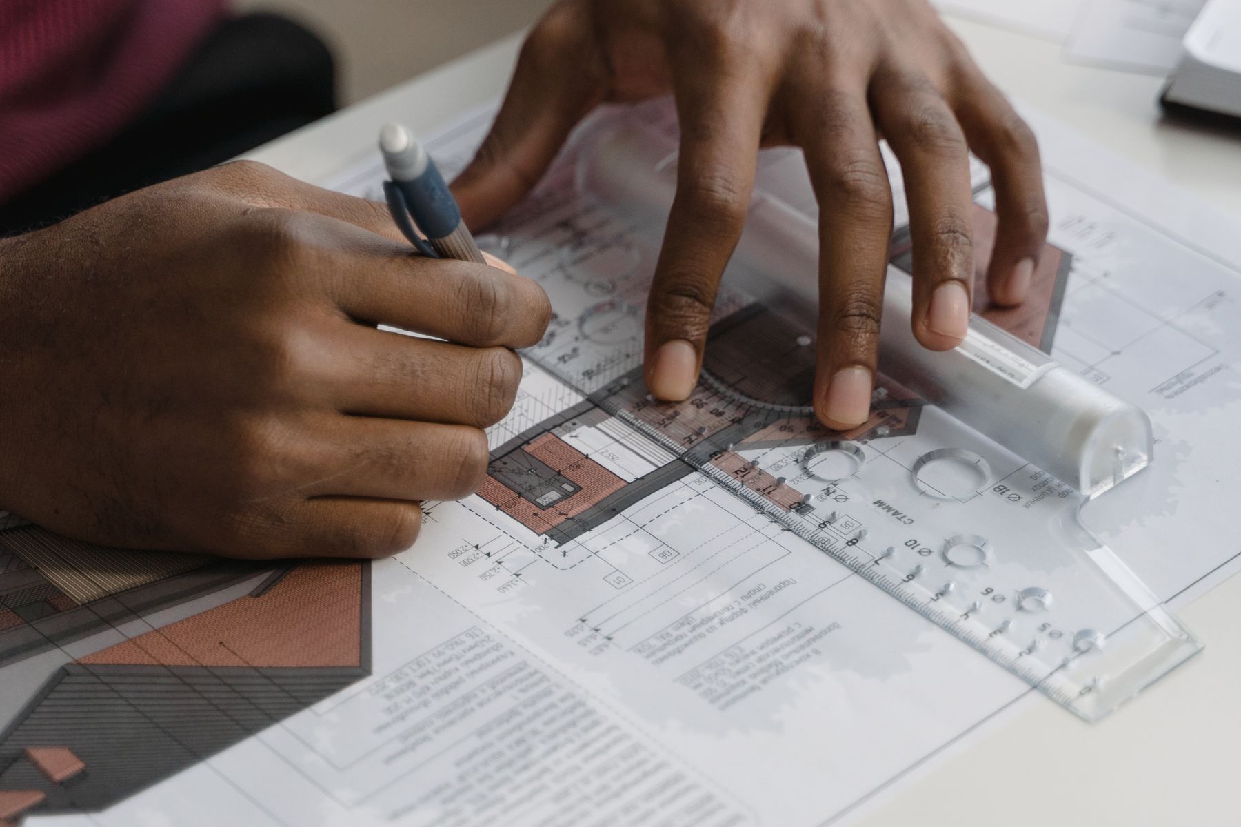 Hands using a ruler and pencil to prepare a detailed project plan